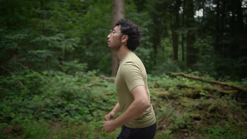 A Young Man Jogging Enthusiastically in a Beautifully Lush and Vibrant Green Forest Setting