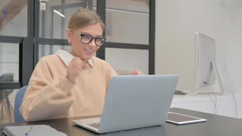 Excited Female Worker Celebrating Success on Laptop in Office