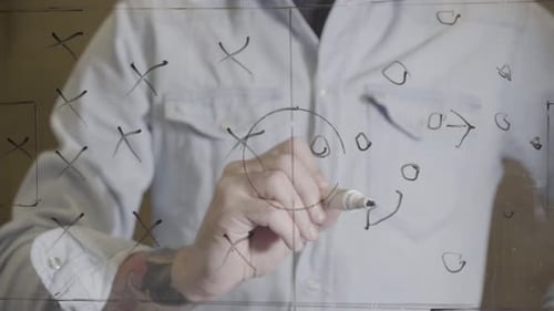 Football Coach Drawing Game Tactics with Arrows Pointing Directions
