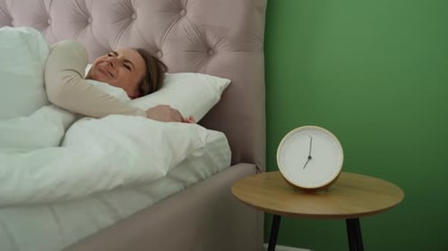 Woman Sleeping in Bed Turns Off Alarm Clock