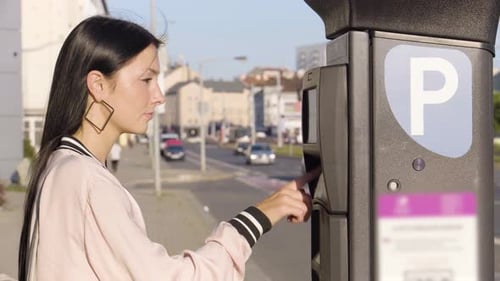 A Young Beautiful Caucasian Woman Pays for Parking at an Invehicle Parking Meter in an Urban Area