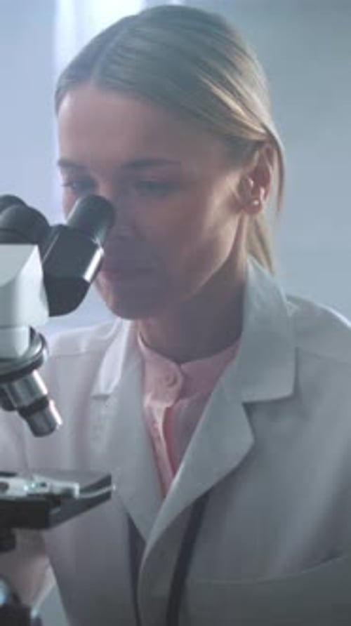 Woman Scientist Looking Through Microscope in Laboratory
