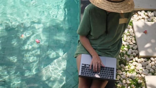 Top View of Woman Sitting in Near the Swimming Pool Using Laptop