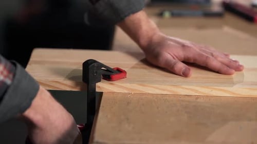 close-up of male hands clamping the board with carpentry clips