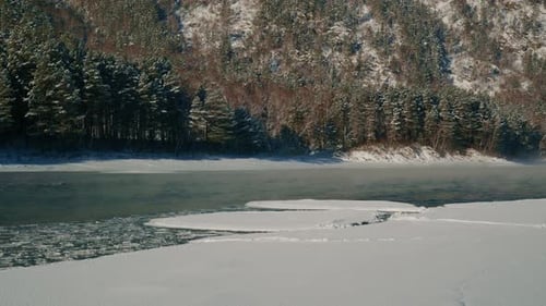 A Serene Winter River Landscape Showcasing Frozen Banks Along with Trees Blanketed in Beautiful Snow