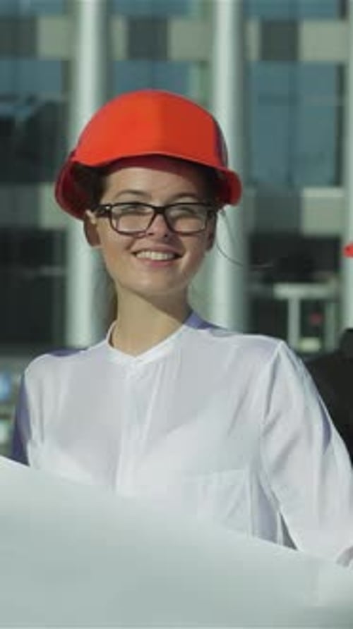 Woman Smiling with Plans Wearing Hard Hat