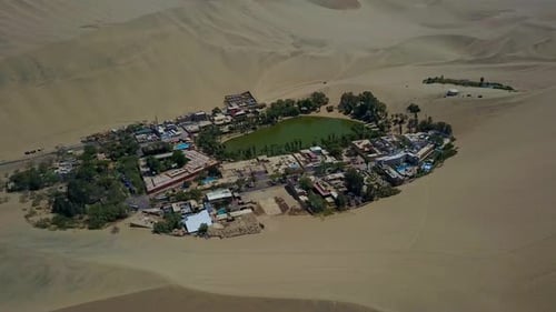 Oasis de Huacachina rodeado de dunas de arena en el desierto de Atacama en Perú. Zumbido aéreo disparado desde arriba.