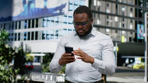 Black Man Disappointed By Bad News on Phone Walking Along City Street