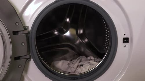 Imagem aproximada de um homem tirando roupas da máquina de lavar