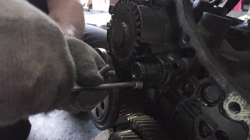 Gloved Hands Repairing Engine Gears