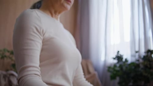 Senior Woman Meditates with Mudra Hands Pose in Quiet Home Studio