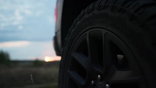 Suv tire and rim with grass with sundown