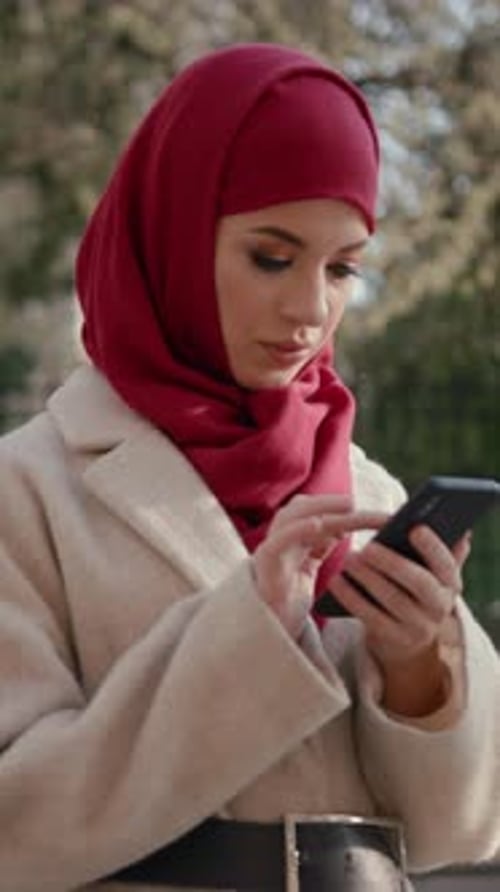 Woman in Headscarf Using Smartphone in City