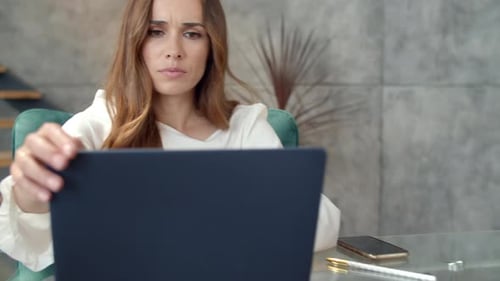 Tired young woman closing laptop after work taking break at home office