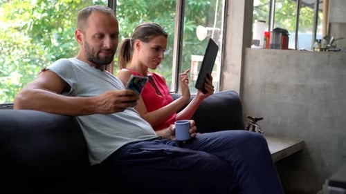 Couple Uses Phone and Tablet Together on Couch