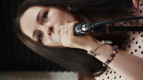 Woman at rehearsal vocal studio singing song into microphone. Vertical video