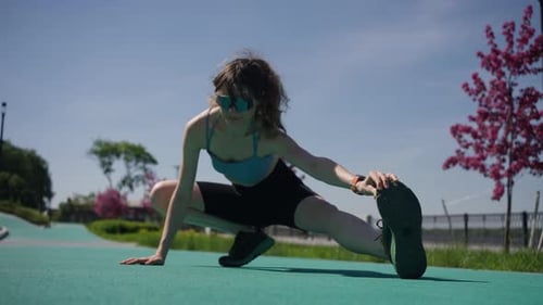 Female Athlete Stretching Dynamically on Verdant Park Ground Warming Muscles Before Highintensity