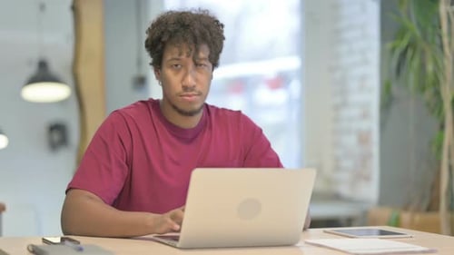 Young Adult Types on Laptop in Bright Indoor Setting