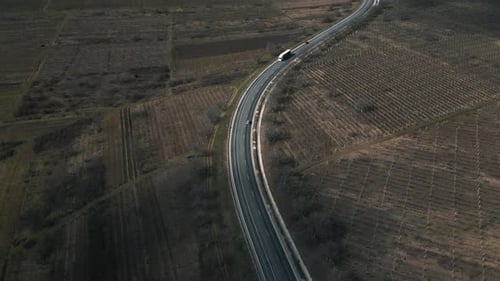 Drohne fliegt bei Sonnenuntergang mit einem fahrenden Geländewagen über einer Autobahn