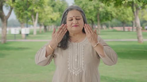 Happy Indian old woman doing breathe in breathe out exercise in park