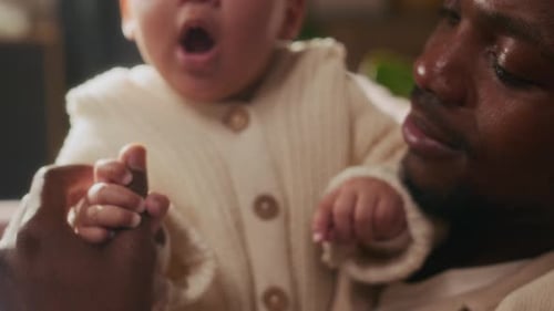 Schwarzer Vater spielt mit süßem Baby, Fokus auf kleine Babyhände