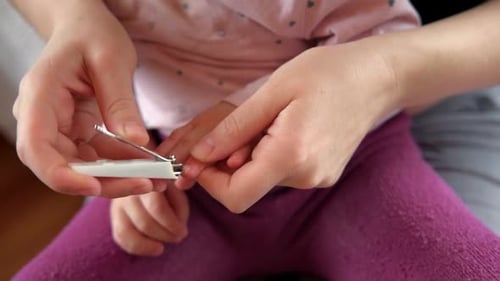 Adult Clipping Child's Fingernails with Clippers Close Up