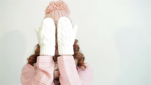 Smiling Woman Peeks Out From Behind White Mittens