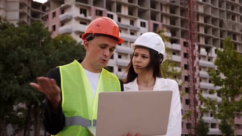 A Builder and an Architect with a Laptop are Standing at a Construction Site