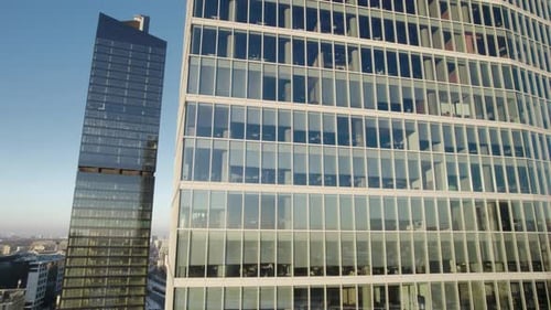 Aerial ascending shot of a modern office building in the business district with glass facade