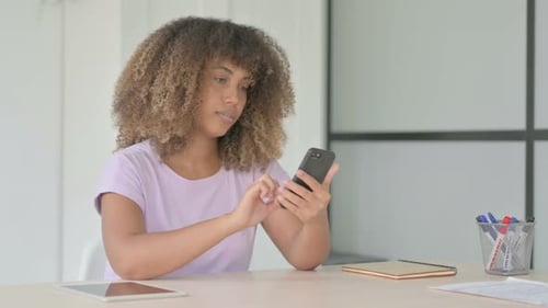 Woman Using Smartphone at Desk Indoors