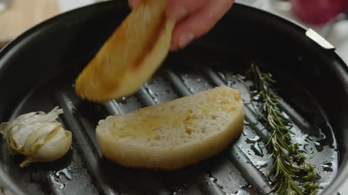 Frying Baguette Slices with Herbs and Garlic on Grill Pan