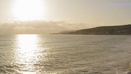 cinematic shot of drone flying towards the horizon over the ocean as the sun rays reflect off the su