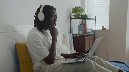 Young adult works on laptop in bedroom