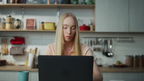 Woman Working at Laptop in Modern Kitchen