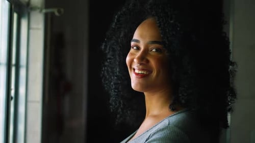 Smiling Woman with Black Curly Hair Looks at Camera