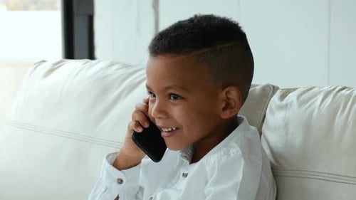 Smiling Boy Talking on Mobile Phone on Couch