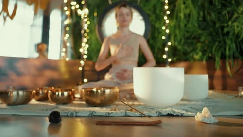 Woman Meditating with Singing Bowls in Peaceful Home
