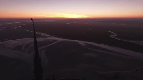 Silhouette of spire of Mont Saint Michel abbey at twilight with bay in background, Normandy in Franc