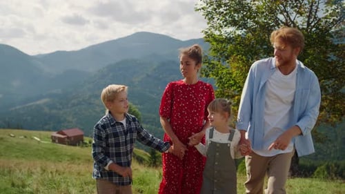 Family enjoying summer vacation walking on green mountain hill with amazing views