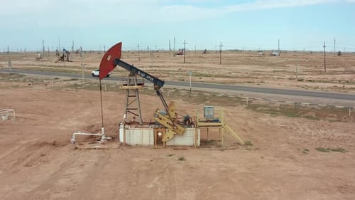 Drone Aerial of Oil Pump Jack Station in Desert Landscape Under Clear Sunny Sky