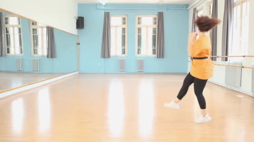 Young brunette dancer practices her dance moves at the studio. Locked off shot.
