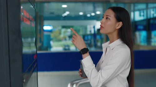 Woman Checks Display Screen in Transit Station