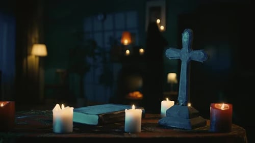 Video, auf dem ein Tisch mit magischen Werkzeugen, Kerzen, Kreuz und einer Buchfigur eines Priesters langsam aufgenommen wird