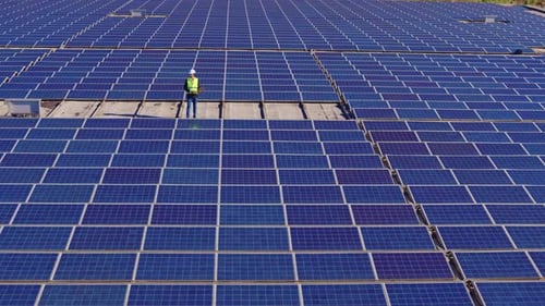 Engineer Inspecting Solar Farm Panels Aerial View