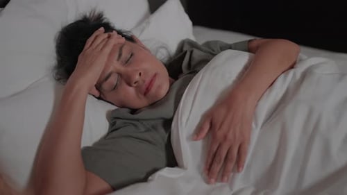 Woman Lying in Bed with a Headache