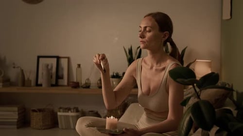 Woman Lights Incense Stick in Serene Setting