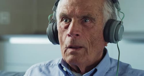 Cinematic close up of happy senior pensioner man is having fun to dance and sing while listening t