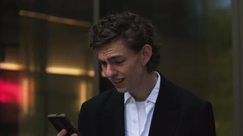 Young Adult Using Phone Outside Mirrored Building