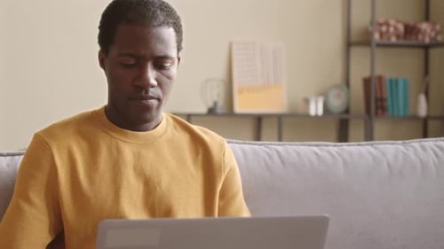 Man Typing on Laptop at Home Receives Call