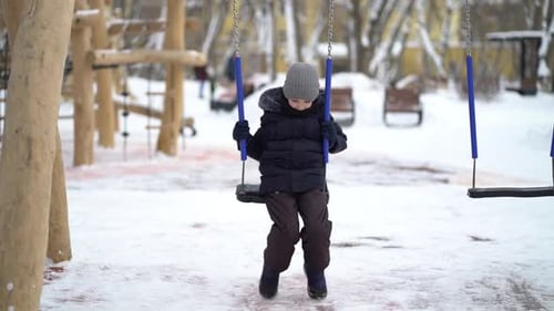 Boy Swinging on a Swing in Winter in the Park